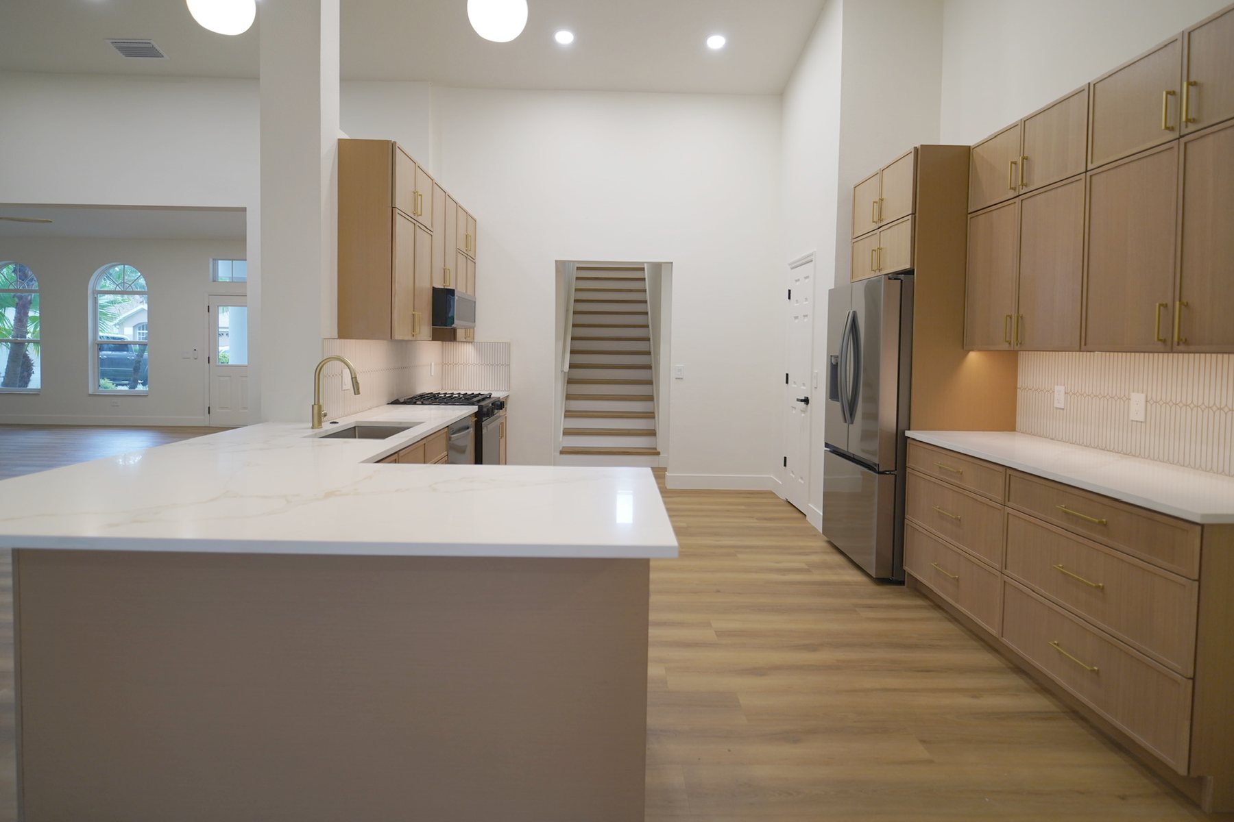 The same kitchen finished: light oak cabinets, a white quartz island and new stainless appliances.